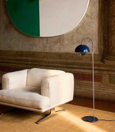 Elegantná stojacia lampa &Tradition vedľa moderného lounge kresla v útulnom interiéri.