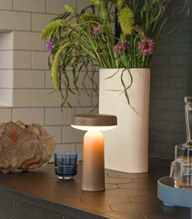 Prenosná stolová lampa Ease od Muuto na modernej kuchynskej pracovnej doske s kvetinovou dekoráciou.