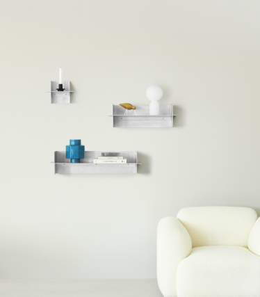 Priehľadné nástenné police Normann Copenhagen s dekoratívnymi doplnkami v minimalistickom obývacom priestore.