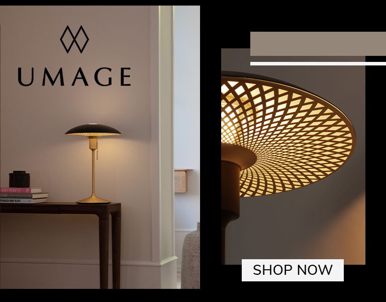 Elegant UMAGE table lamp with gold base and patterned shade on a wooden console table, softly illuminating a modern interior, with text ‘Shop Now’.